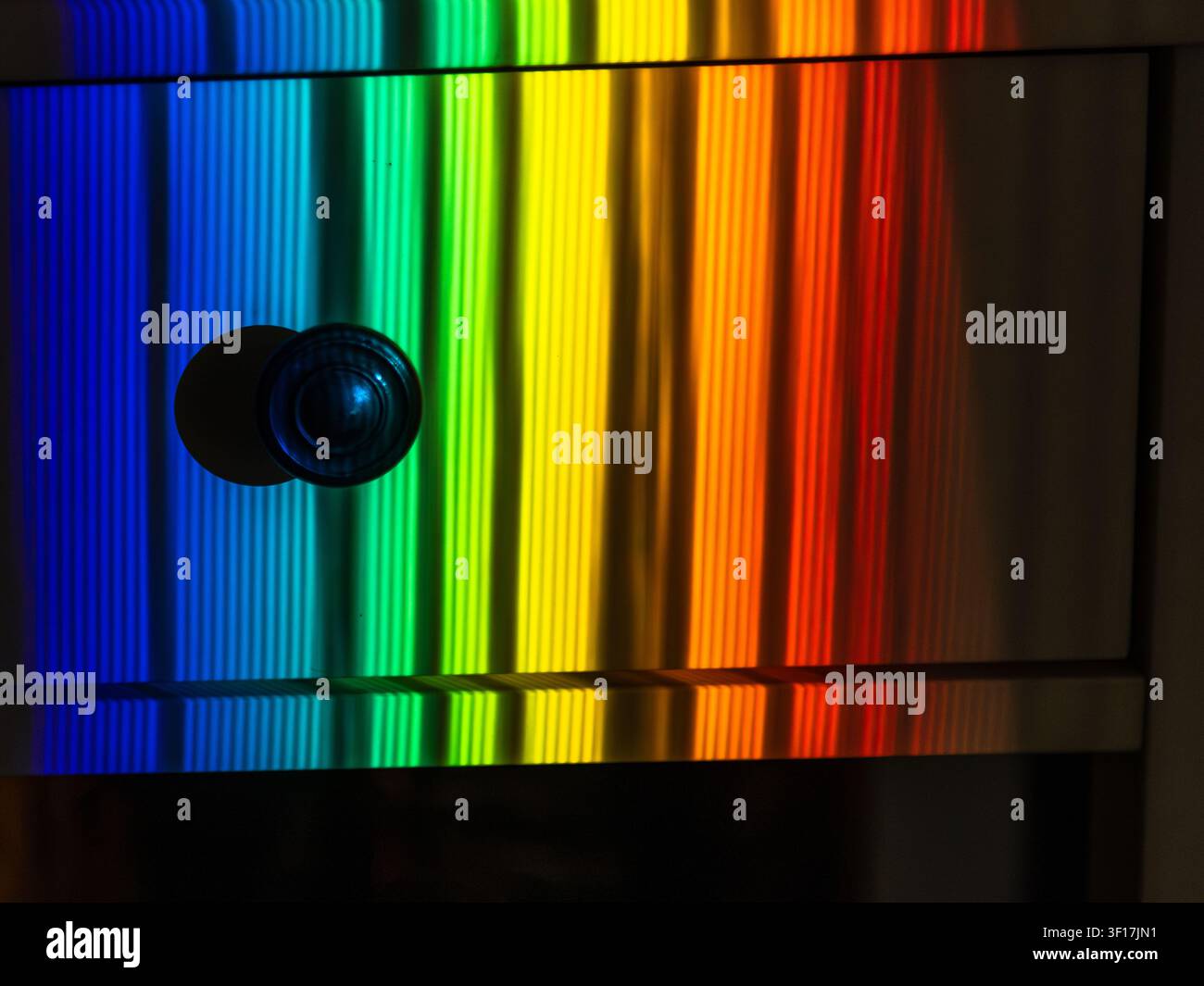 Spettro di luce arcobaleno astratto riflesso su una superficie metallica lucida, che crea uno sfondo geometrico colorato con sfumature vivaci Foto Stock