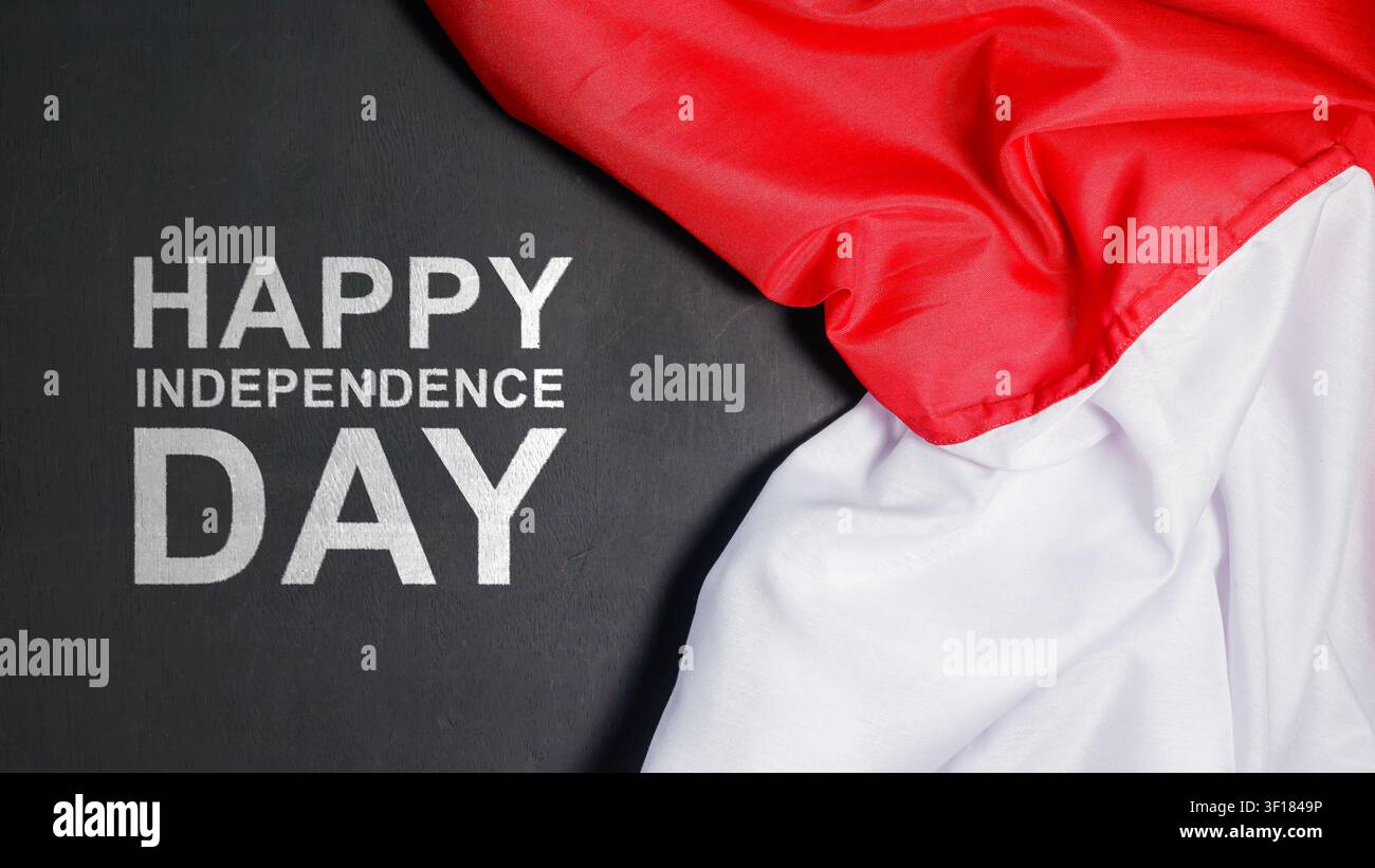 Un design di biglietto di auguri patriottico con il testo Happy Independence Day su uno sfondo di legno nero accanto a una bandiera rossa e bianca. Foto di alta qualità Foto Stock