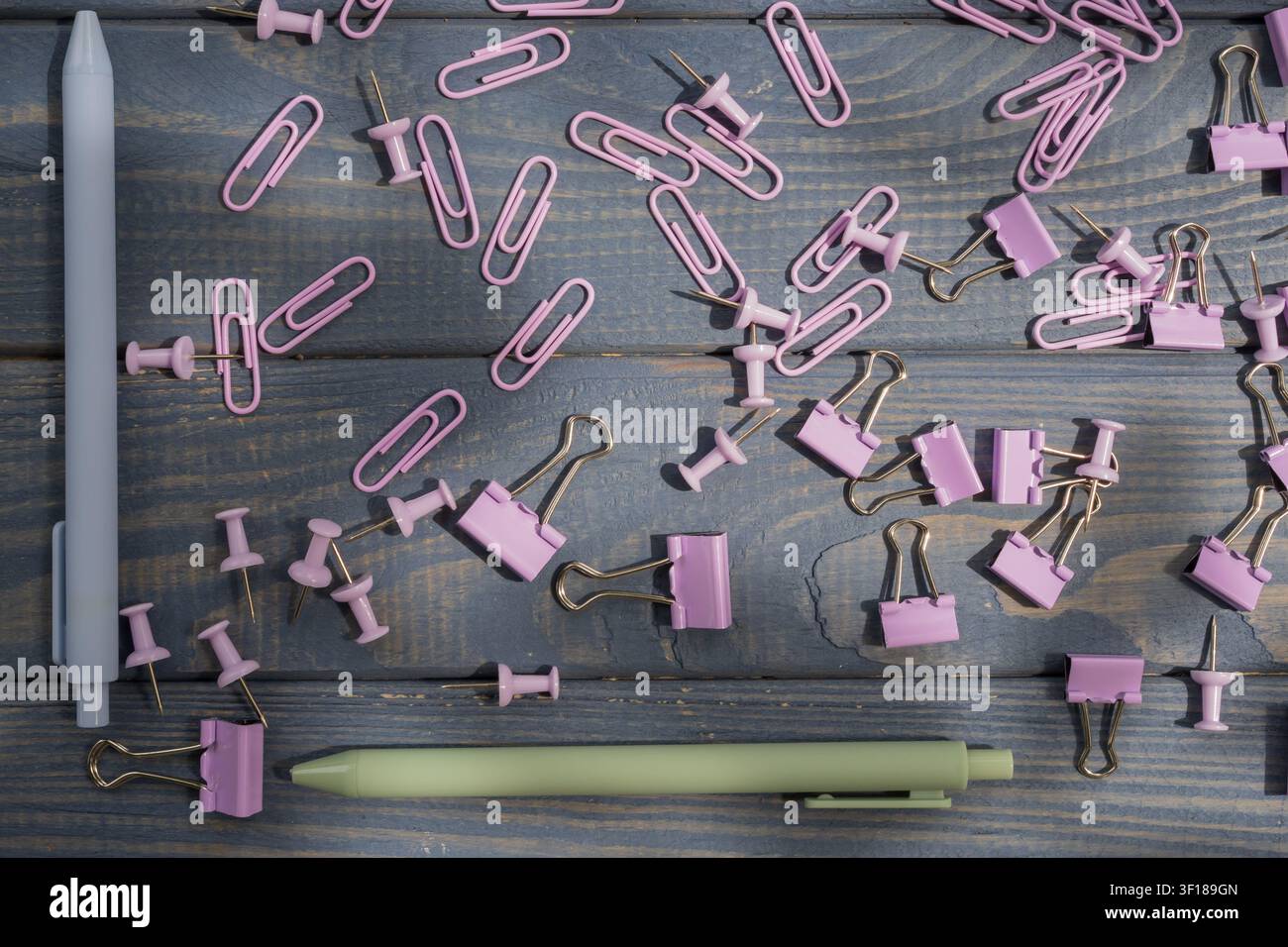 Accessori per la cancelleria in pastello tra cui graffette, pinze per raccoglitori, spilli e penne per l'organizzazione dell'ufficio, lo studio e le forniture scolastiche. Foto Stock