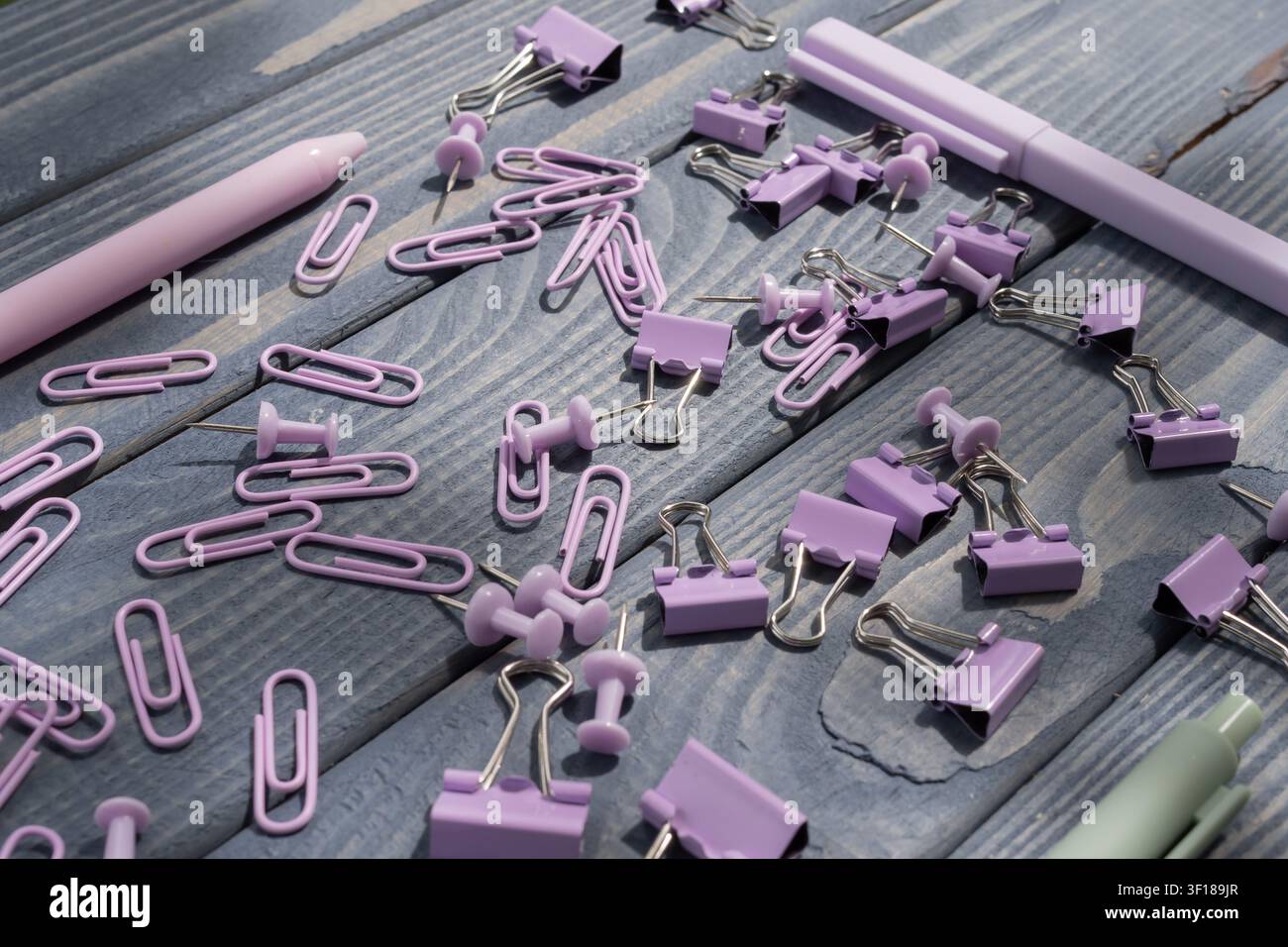 Accessori per la cancelleria in pastello tra cui graffette, pinze per raccoglitori, spilli e penne per l'organizzazione dell'ufficio, lo studio e le forniture scolastiche. Foto Stock