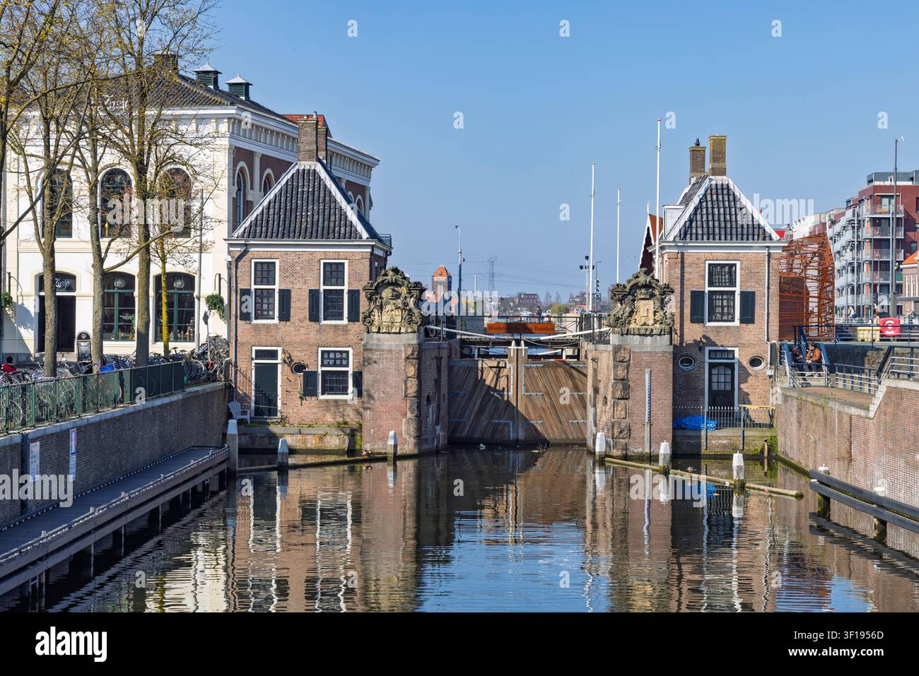 Zaandam, Paesi Bassi. Le porte storiche dell’Oude Sluis nel centro città, con tradizionali case di chiuse in mattoni e il riflesso calmo del canale. Foto Stock