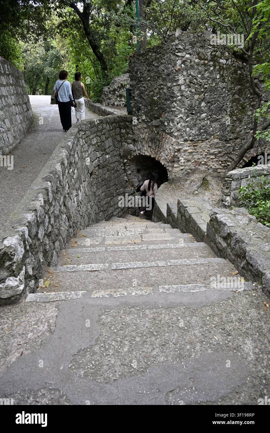 Percorso, gradini in pietra e arco in pietra che attraversano una struttura a torretta, persone in esplorazione Foto Stock