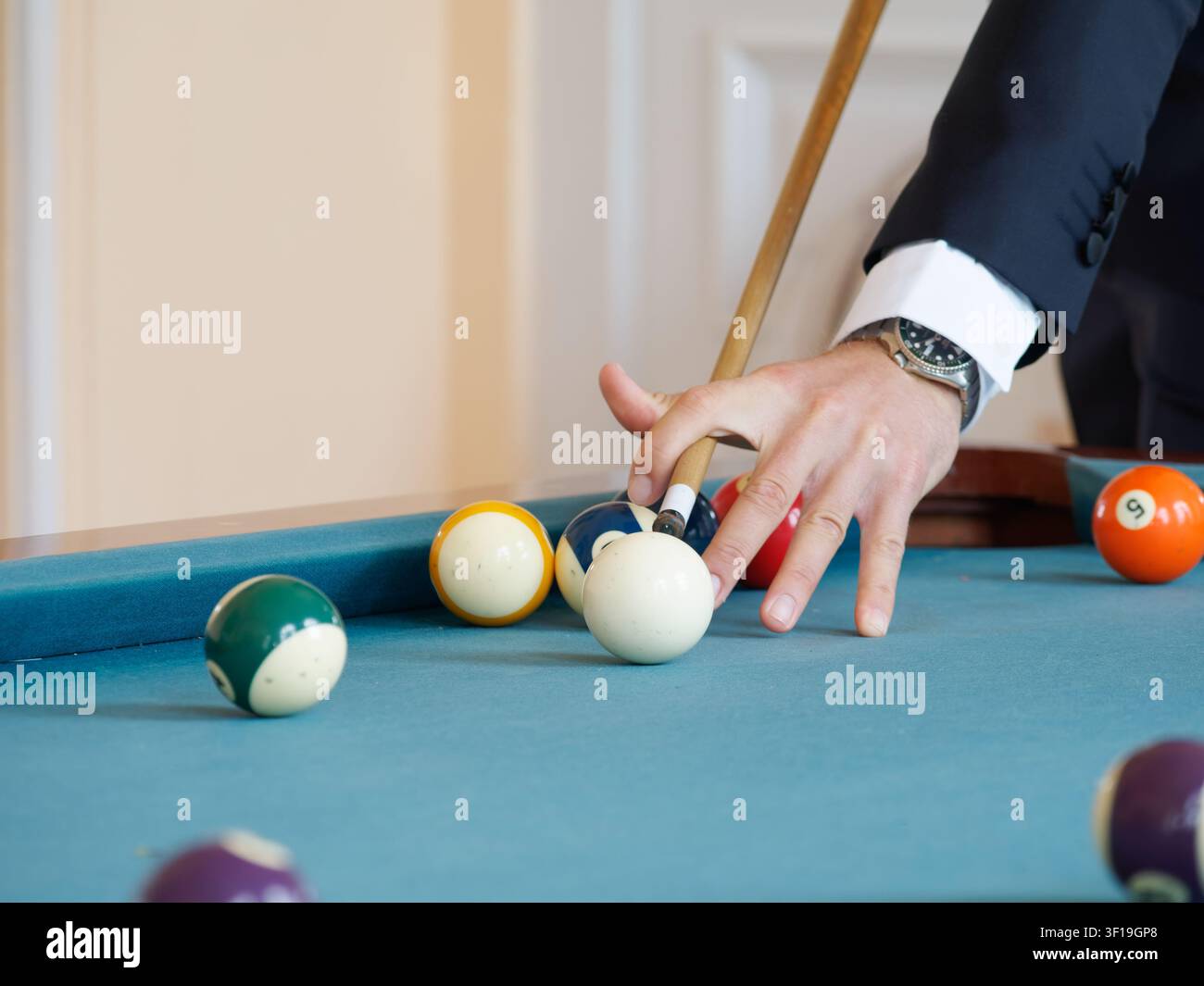 Giocatore di biliardo che posiziona la palla bianca per un colpo su un tavolo da biliardo Foto Stock