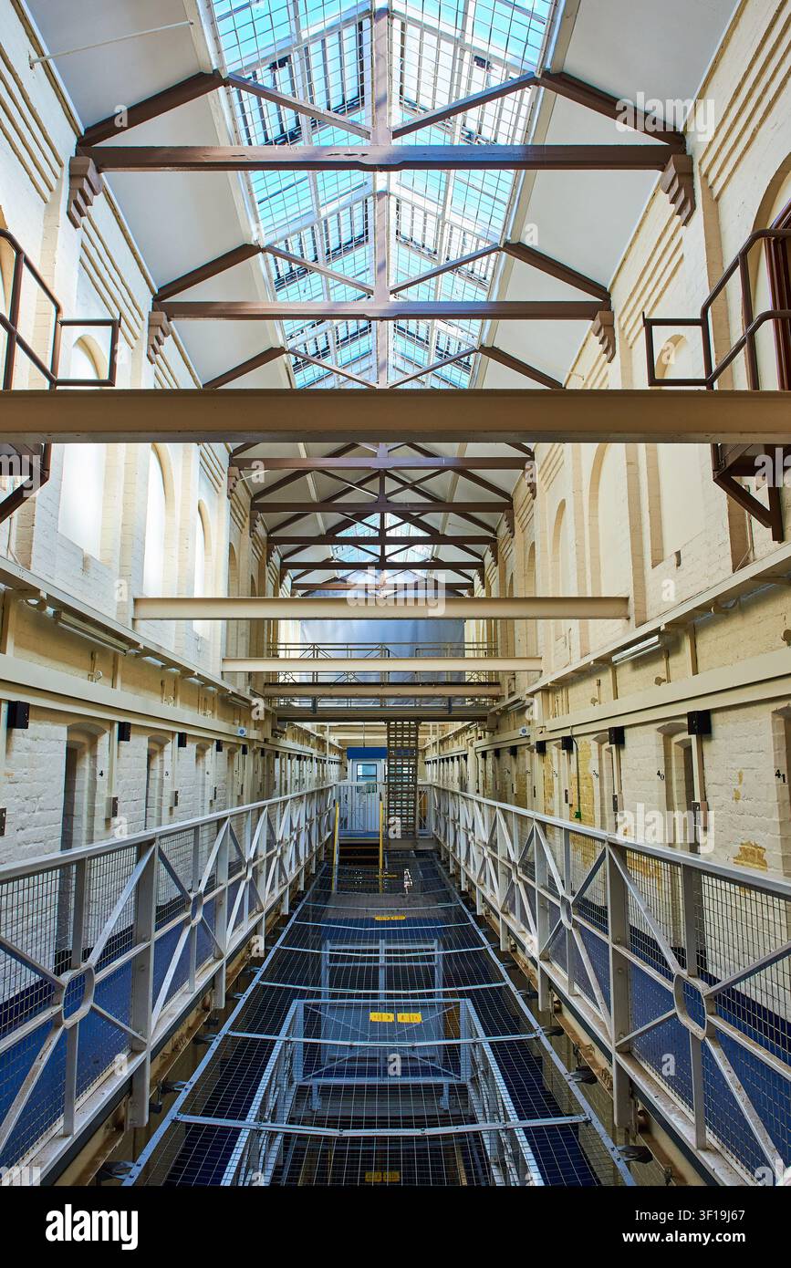 Una vista interna simmetrica che guarda giù lungo il corridoio a più livelli del blocco delle celle e delle passerelle della storica prigione dismessa di Shrewsbury, Shropshire, E Foto Stock
