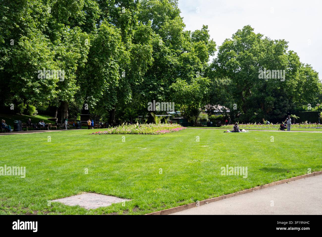 Persone che si rilassano sul prato dei Victoria Embankment Gardens, parco fluviale lungo il Tamigi tra le stazioni di Charing Cross e Blackfriars, Londra UK Foto Stock