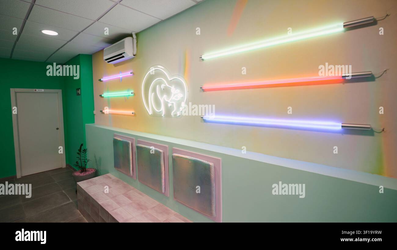Vivace area d'attesa di una clinica veterinaria con luci al neon colorate e logo animale Foto Stock
