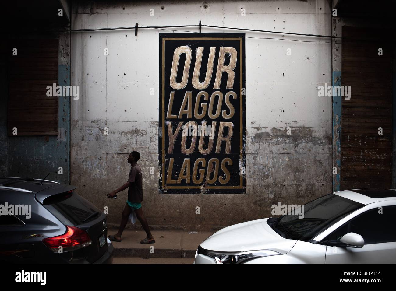 Lagos, Nigeria – 13 giugno 2026. Un pedone passa davanti a un muro con l'iscrizione "LA NOSTRA LAGOS LA TUA LAGOS" a Lagos Foto Stock