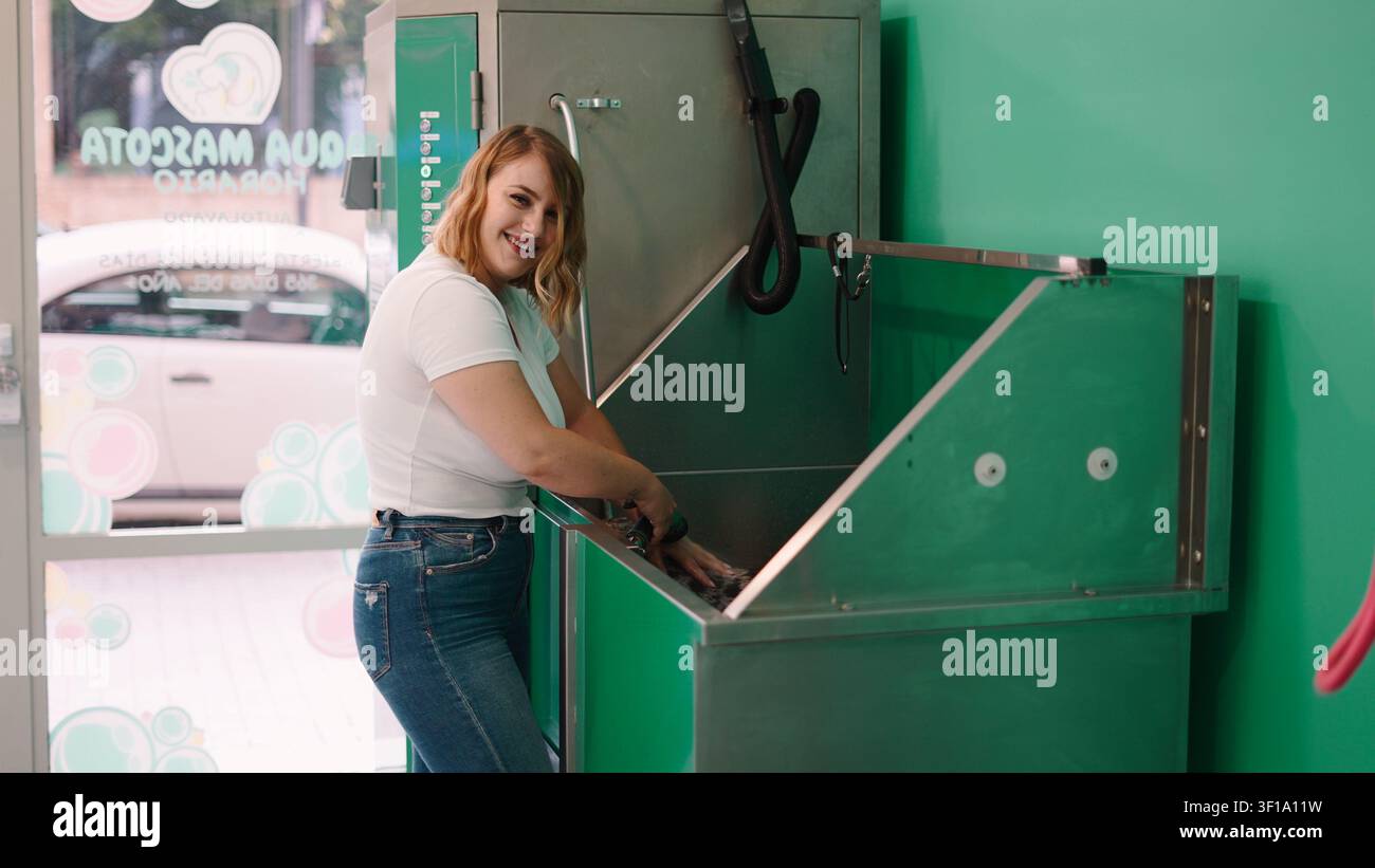 Donna che lava il suo cane in una stazione di lavaggio per animali domestici self-service Foto Stock