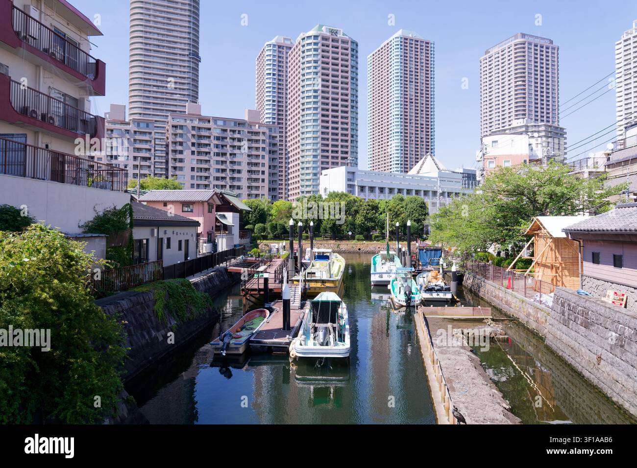 Canale storico di Tokyo, Giappone, fiancheggiato da case tradizionali per barche e moderni grattacieli residenziali a Tsukishima Foto Stock