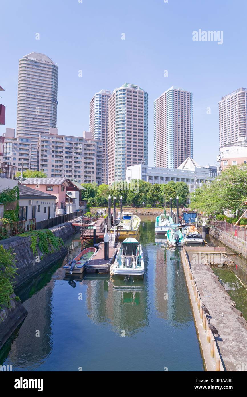 Tokyo Giappone vista verticale di un canale storico con case tradizionali per barche e grattacieli residenziali, che illustrano la coesistenza dell'eredità di Edo Foto Stock