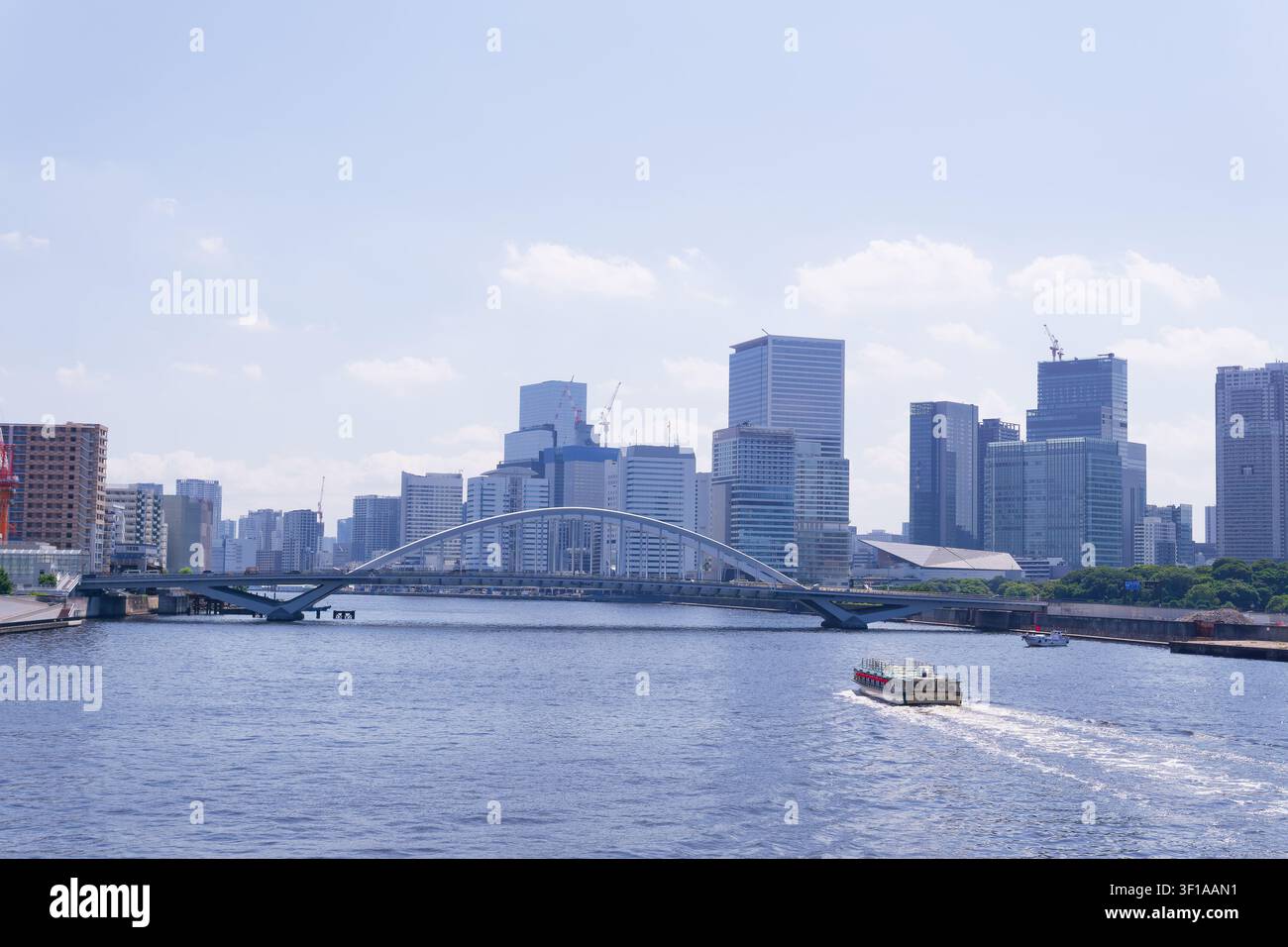 Tokyo Giappone fiume Sumida con un tradizionale yakatabune che naviga sotto il ponte Eitai sullo sfondo di grattacieli moderni in una luminosa giornata estiva Foto Stock