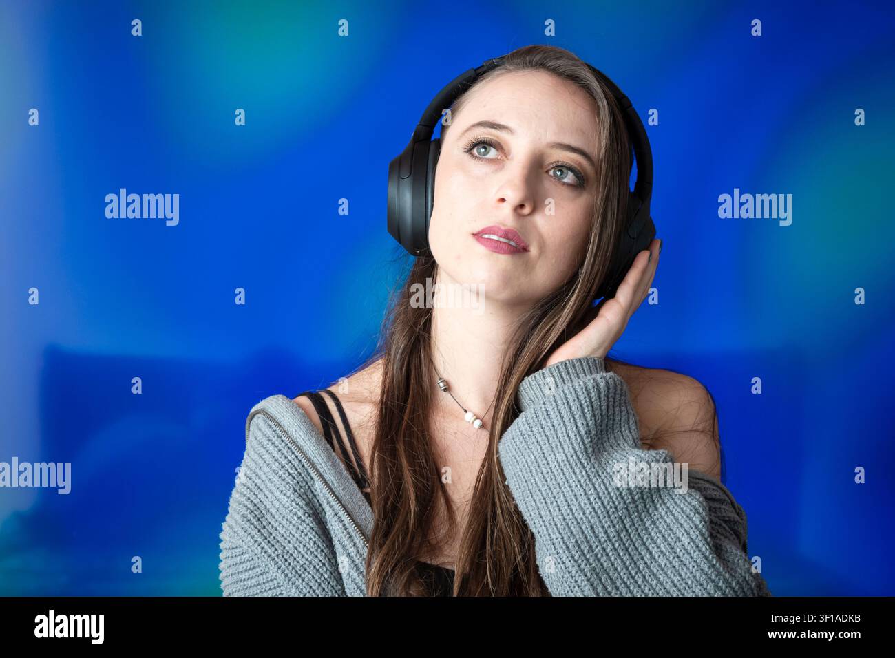 Giovane donna ispirata che ascolta musica e guarda verso l'alto con cuffie senza fili Foto Stock