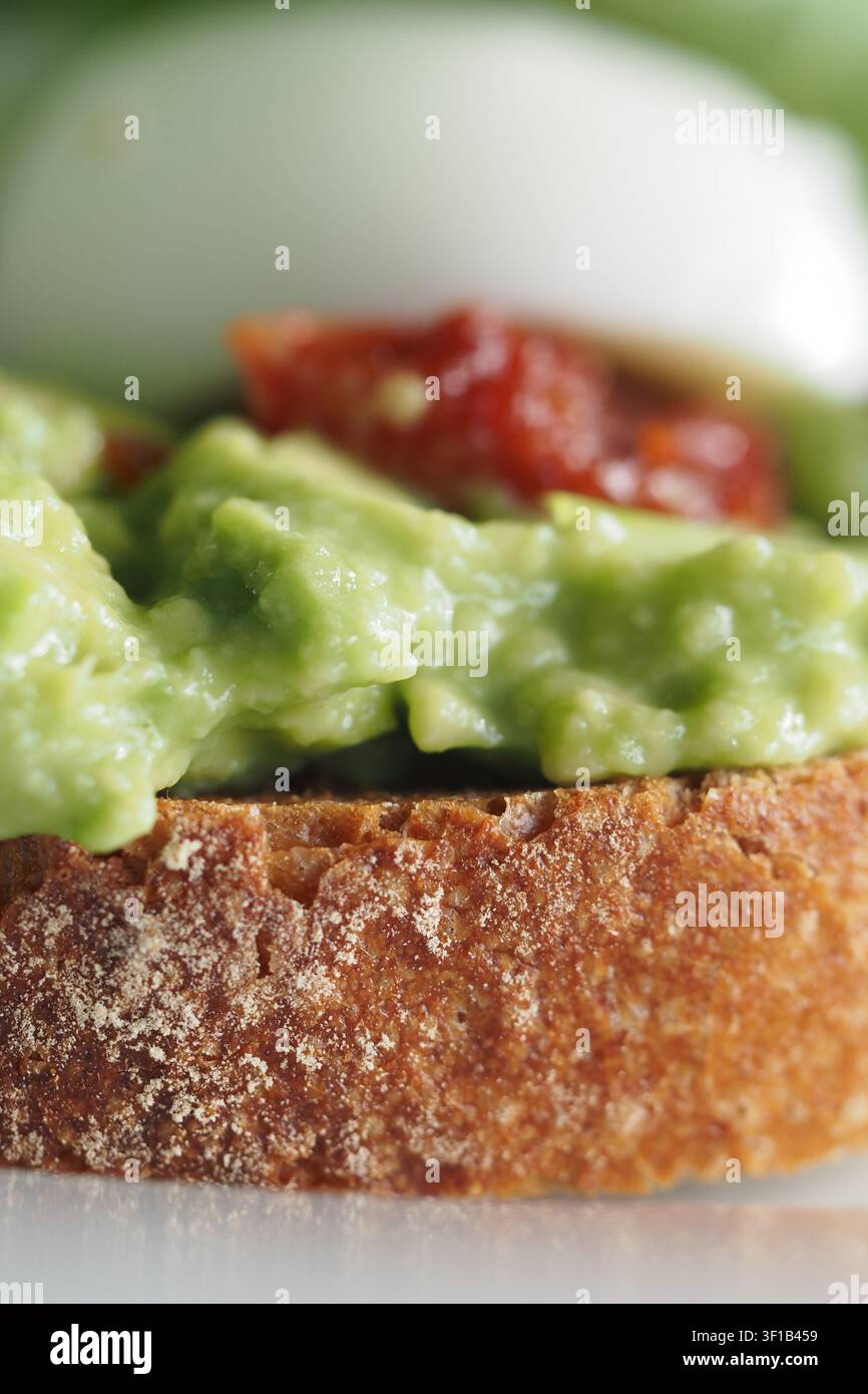 Fetta di toast all'avocado con una crema di avocado cremosa su una spessa fetta di pane di lievito naturale tostato Foto Stock