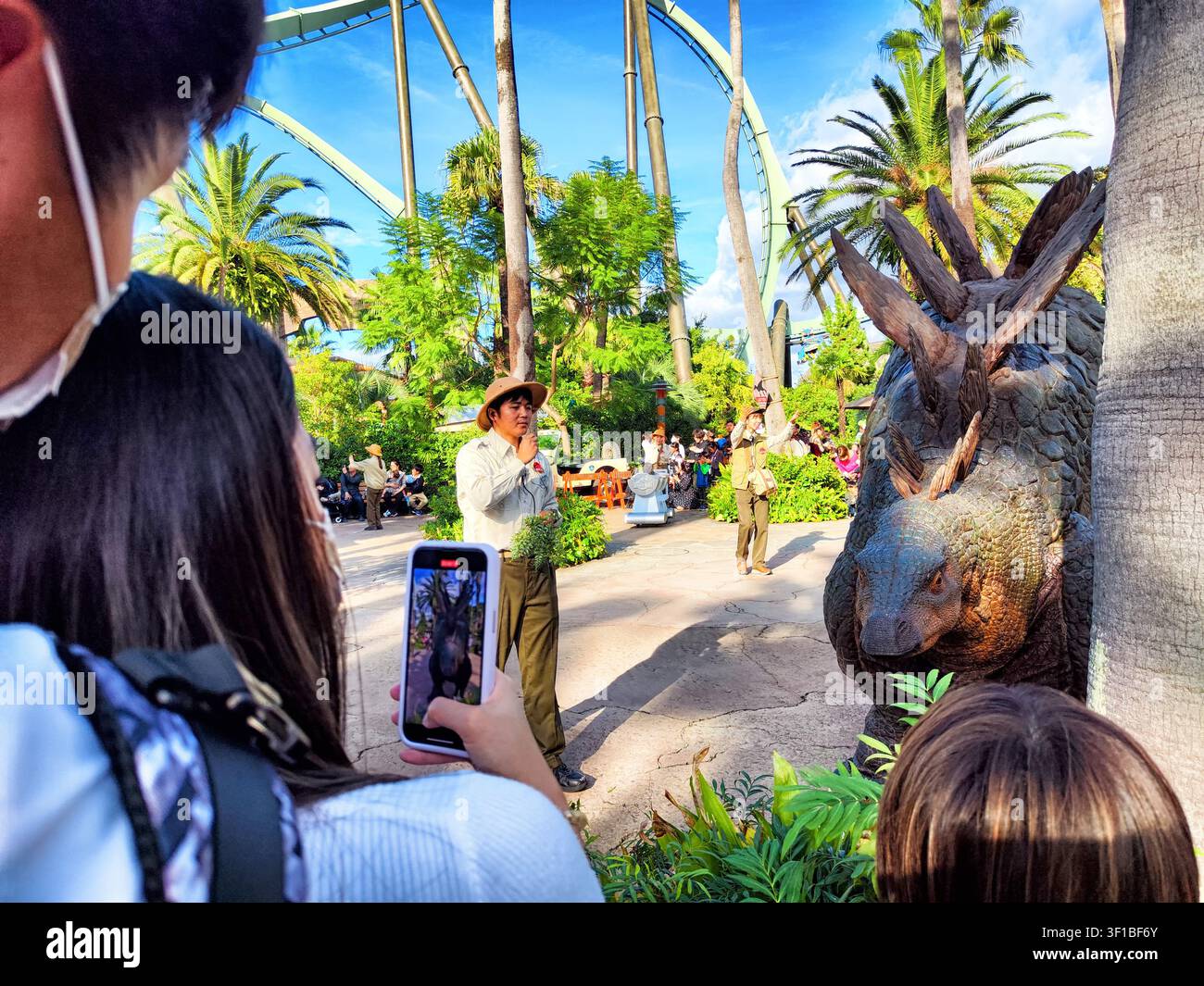Giappone, Osaka – 28 ottobre 2024: Gli ospiti godono di un vivace incontro con i dinosauri, interagendo con il personale e osservando creature preistoriche nel parco panoramico. Foto Stock