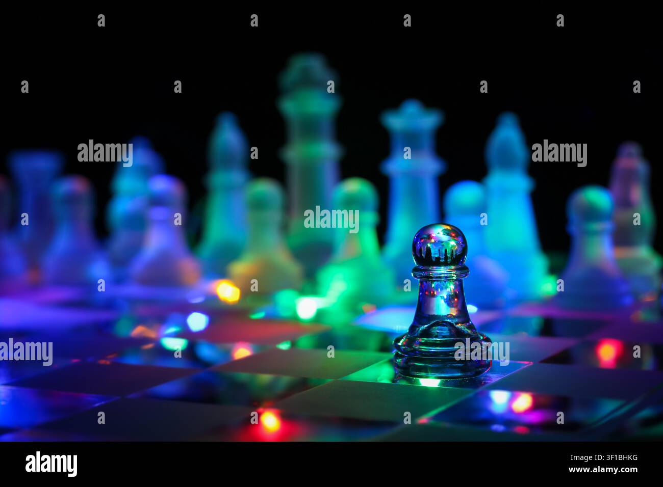Pedine di scacchi in vetro su una scacchiera con illuminazione di sfondo bokeh colorata Foto Stock