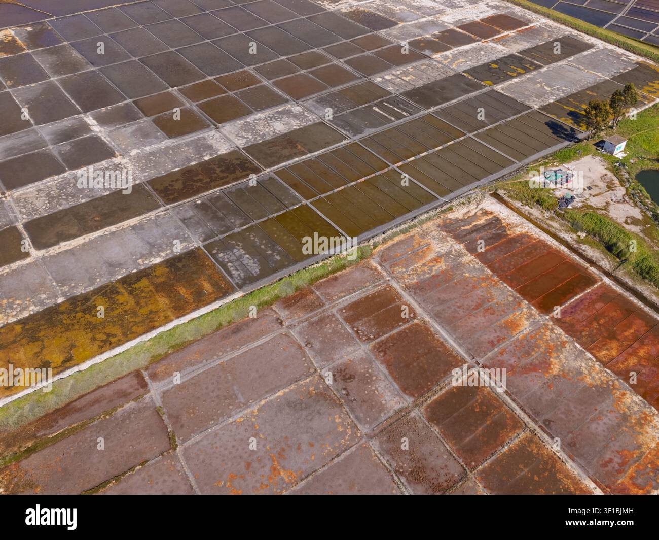Vista aerea delle saline di Aveiro con bacini di evaporazione geometrici che mostrano colori e texture variabili ad Aveiro, distretto di Aveiro, Portogallo. Foto Stock