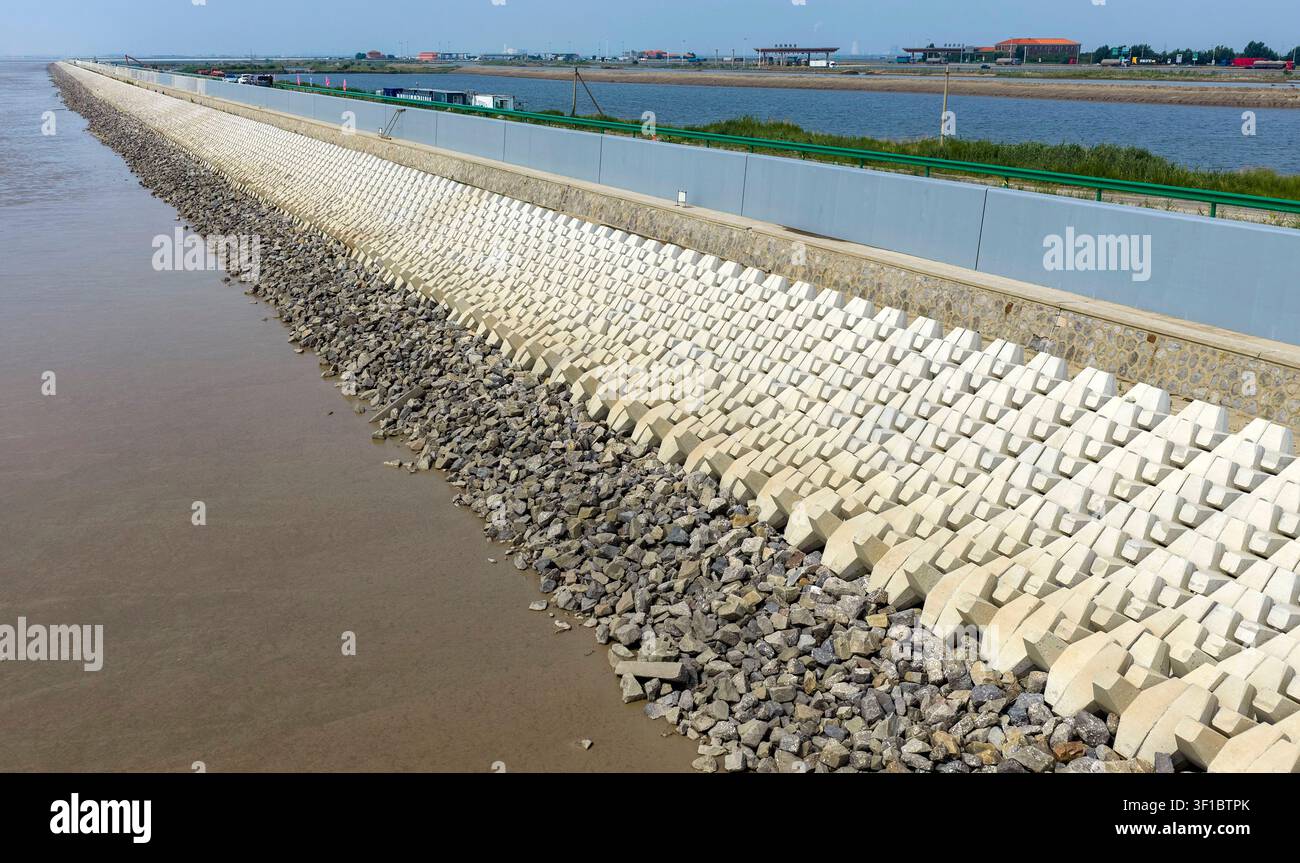 Tianjin. 12 luglio 2026. Una foto aerea scattata il 12 luglio 2026 mostra una vista della prima fase di un progetto di diga costiera nell’area nuova di Binhai a Tianjin, Cina settentrionale. La prima fase del progetto di diga costiera nell’area nuova di Binhai è stata completata. Estesa per 3,4 chilometri, la nuova diga vanta un’altezza della cresta di 9,2 metri, circa 2 metri più alta di quella originale, consentendo di affrontare meglio i rischi combinati di tifoni, tempeste e ondate di tempesta. Credit: Zhao Zishuo/Xinhua/Alamy Live News Foto Stock