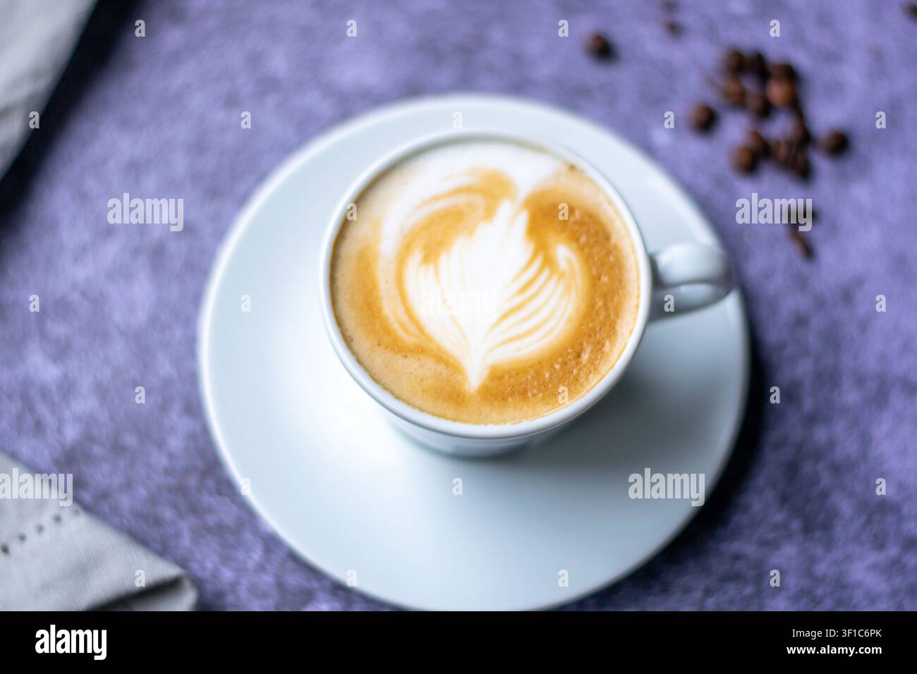 Close-up di un cappuccino con latte art a forma di cuore in una tazza di ceramica bianca. Foto Stock