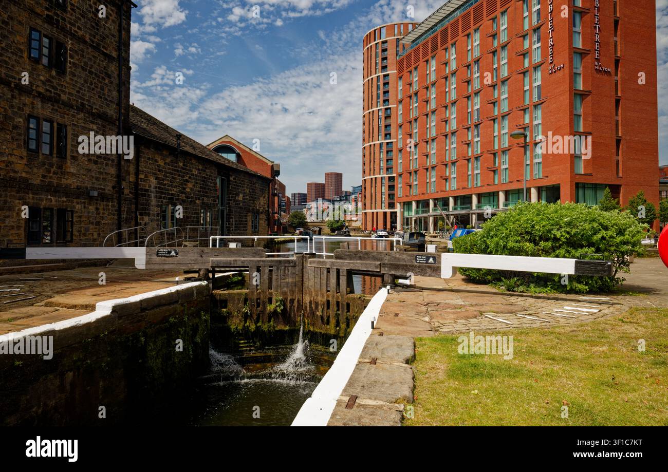 Un canale con chiuse in un contesto urbano con uffici sul lungofiume, appartamenti e bar, Granary Wharf, Leeds, West Yorkshire, Inghilterra. Foto Stock