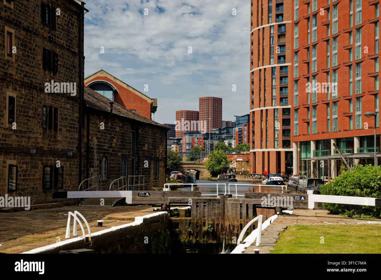 Un canale con chiuse in un contesto urbano con uffici sul lungofiume, appartamenti e bar, Granary Wharf, Leeds, West Yorkshire, Inghilterra. Foto Stock