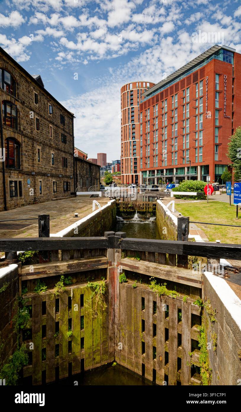 Un canale con chiuse in un contesto urbano con uffici sul lungofiume, appartamenti e bar, Granary Wharf, Leeds, West Yorkshire, Inghilterra. Foto Stock