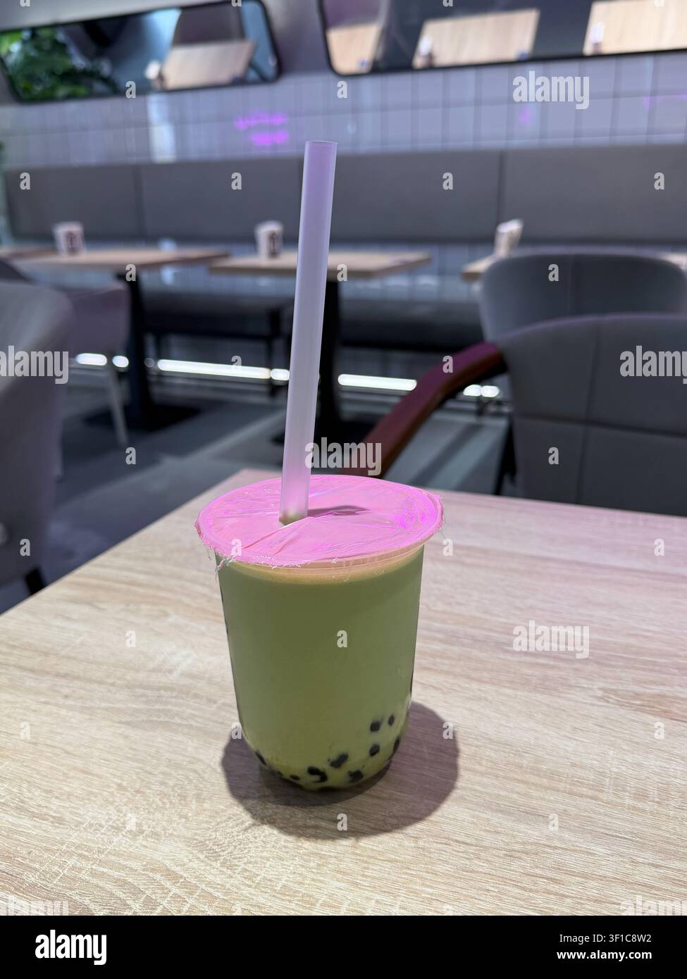 Tè alle bolle al matcha con perle di tapioca servito su un tavolo da caffè in un interno moderno con sfondo sfocato. Cultura del caffè, tendenza alimentare, stile di vita Foto Stock