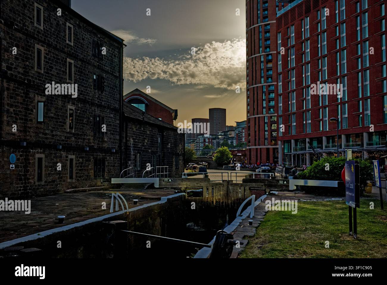 Il sole della sera inizia a svanire oscurando i cieli sopra un canale urbano con chiuse, Granary Wharf, Leeds, West Yorkshire. Foto Stock