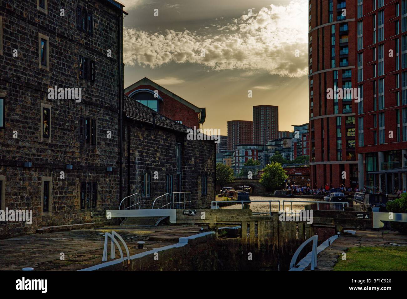Il sole della sera inizia a svanire oscurando i cieli sopra un canale urbano con chiuse, Granary Wharf, Leeds, West Yorkshire. Foto Stock