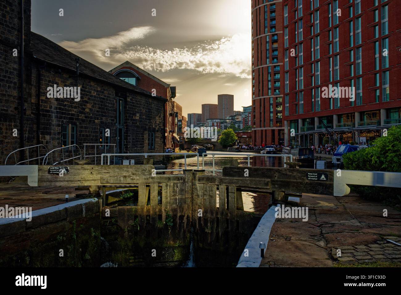 Il sole della sera inizia a svanire oscurando i cieli sopra un canale urbano con chiuse, Granary Wharf, Leeds, West Yorkshire. Foto Stock
