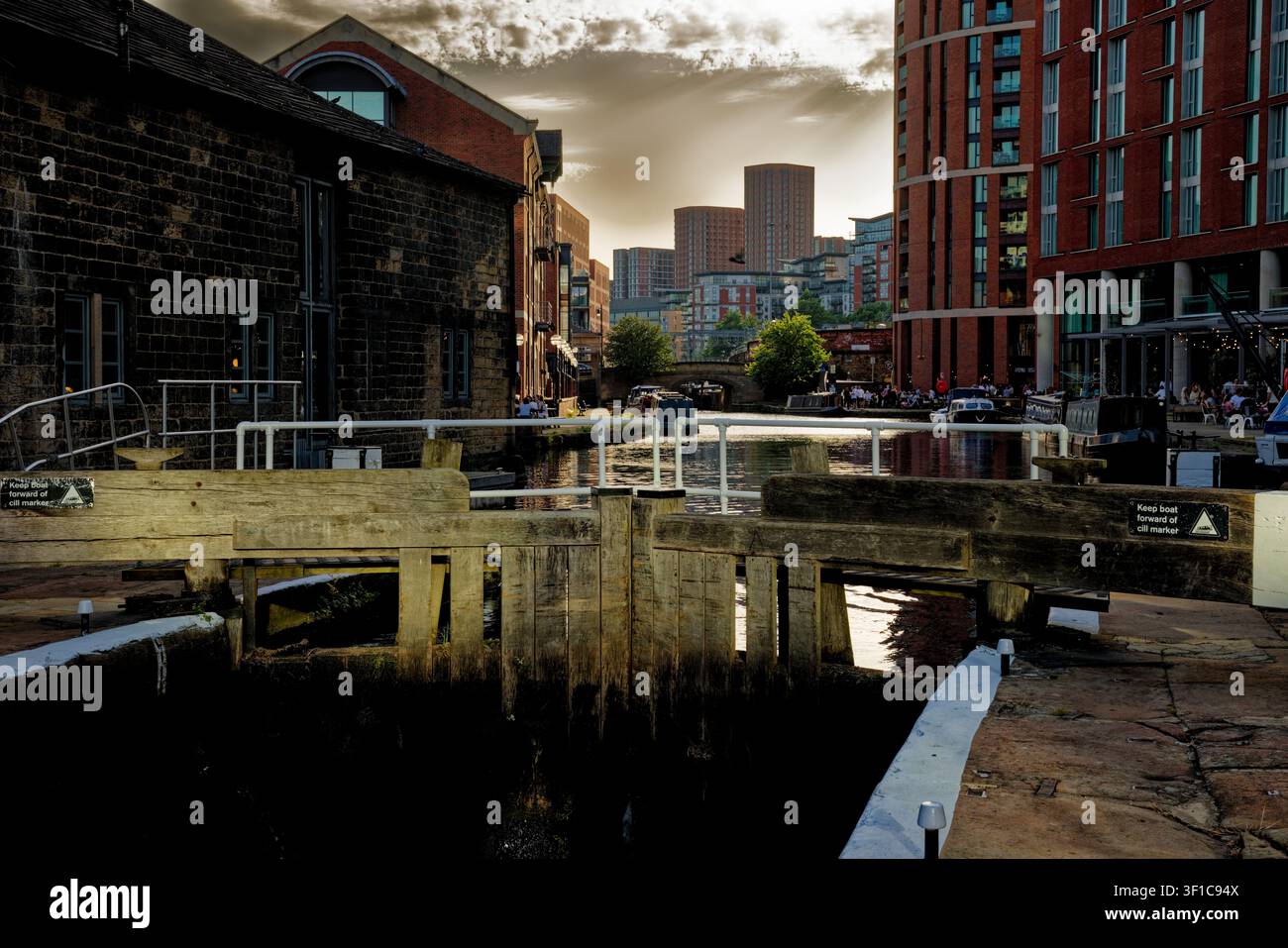Il sole della sera inizia a svanire oscurando i cieli sopra un canale urbano con chiuse, Granary Wharf, Leeds, West Yorkshire. Foto Stock