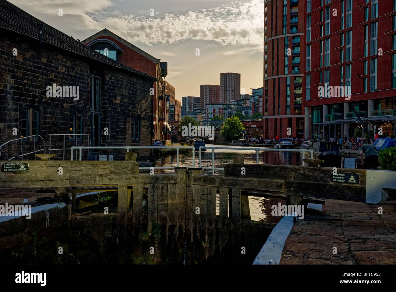 Il sole della sera inizia a svanire oscurando i cieli sopra un canale urbano con chiuse, Granary Wharf, Leeds, West Yorkshire. Foto Stock