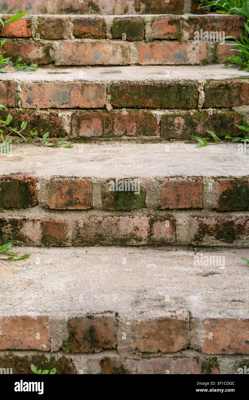 Una vista ravvicinata di gradini in mattoni invecchiati con pianelli in cemento consumati, che mostrano texture rustiche e superfici consumate dalle intemperie Foto Stock