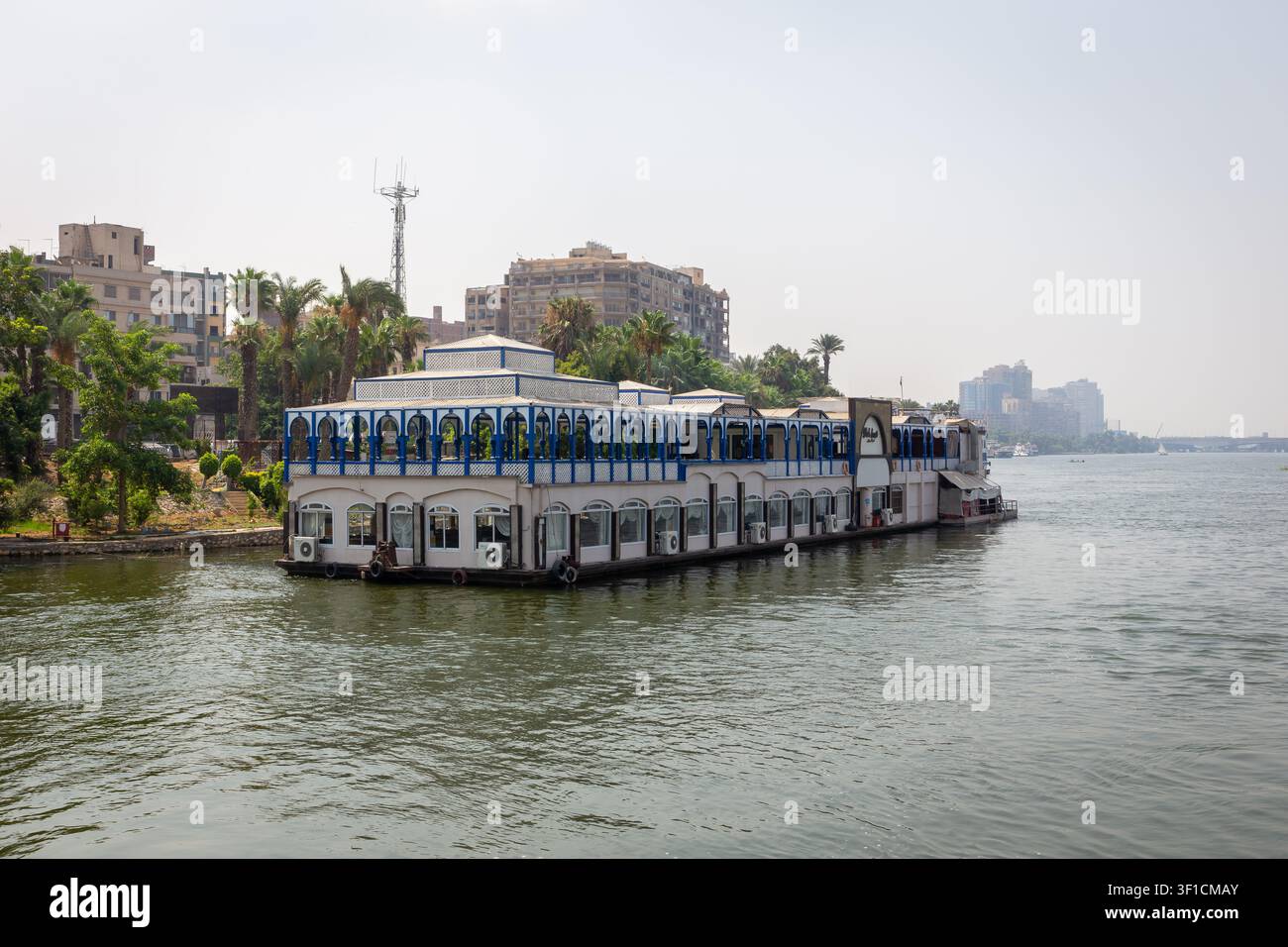 Il Cairo, Egitto, 25.07.21. Barca da pesca - Ristorante galleggiante Abouzeid ormeggiato sulla riva del Nilo con lo skyline del Cairo sullo sfondo. Foto Stock