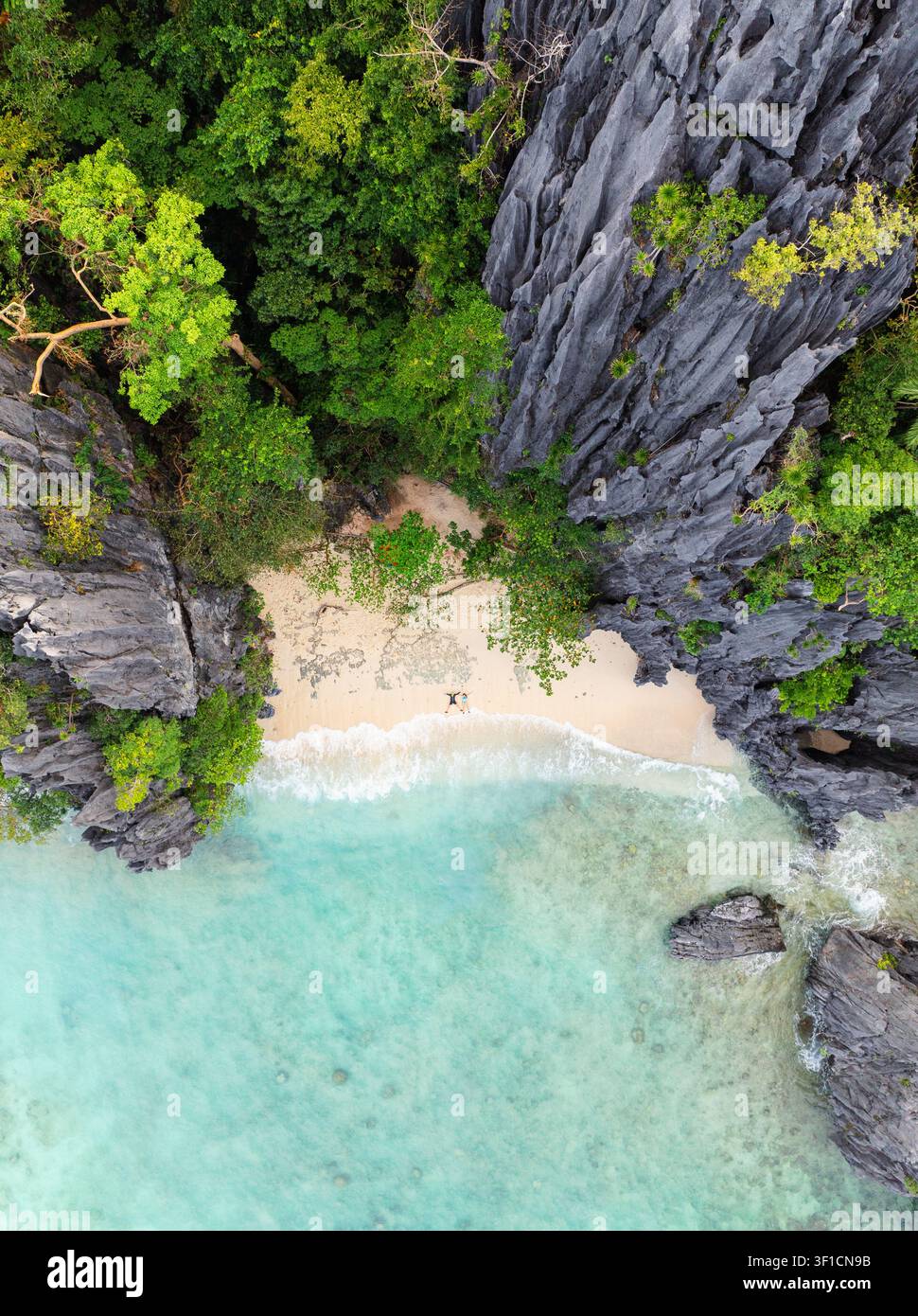 Vista aerea di una coppia sdraiata sulla sabbia in posizione a stella su una spiaggia di Shimizu Island, circondata da scogliere di calcare e acqua turchese a El Foto Stock