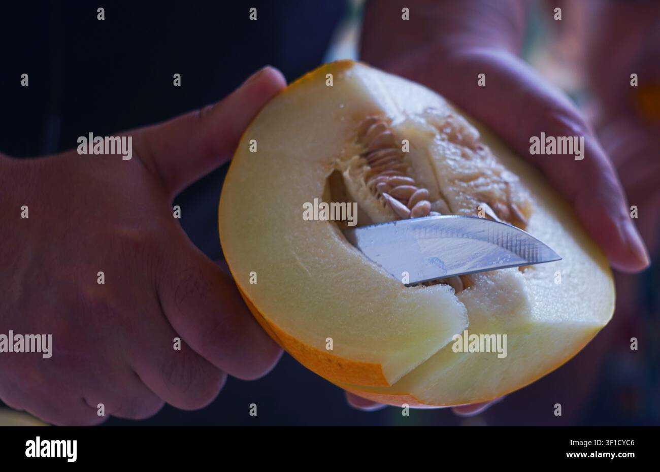 Un uomo taglia un melone giallo Foto Stock