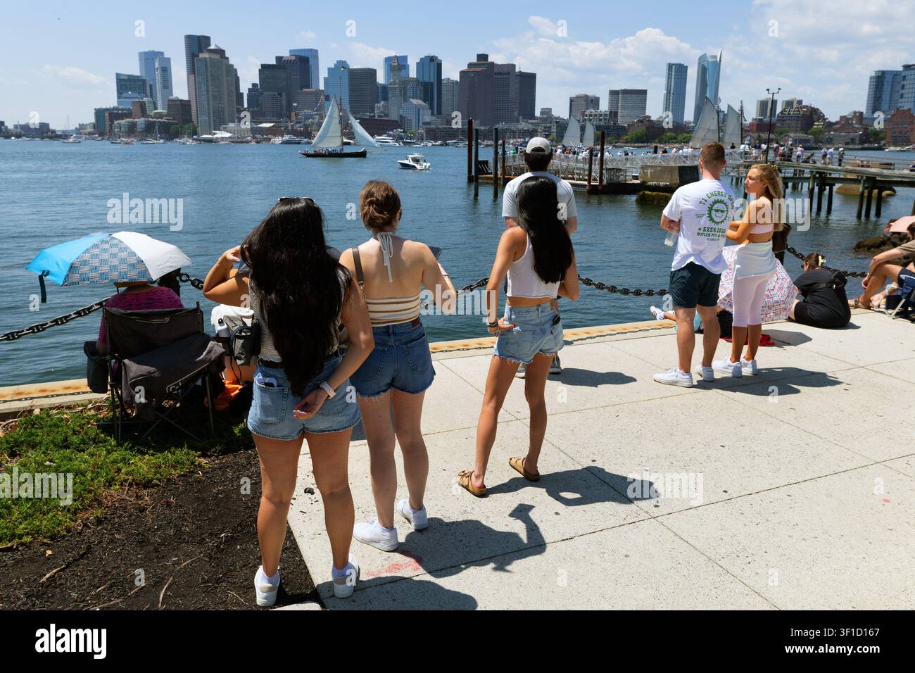 Gli spettatori osservano la Parata delle Vele dal lungomare di East Boston, con lo skyline del centro di Boston dall'altra parte del porto. Foto Stock