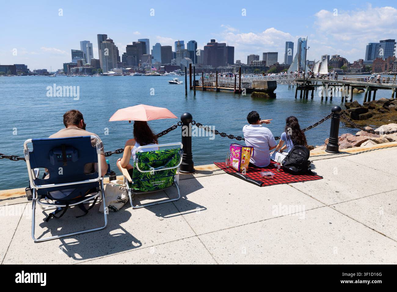 Gli spettatori osservano la Parata delle Vele dal lungomare di East Boston, con lo skyline del centro di Boston dall'altra parte del porto. Foto Stock