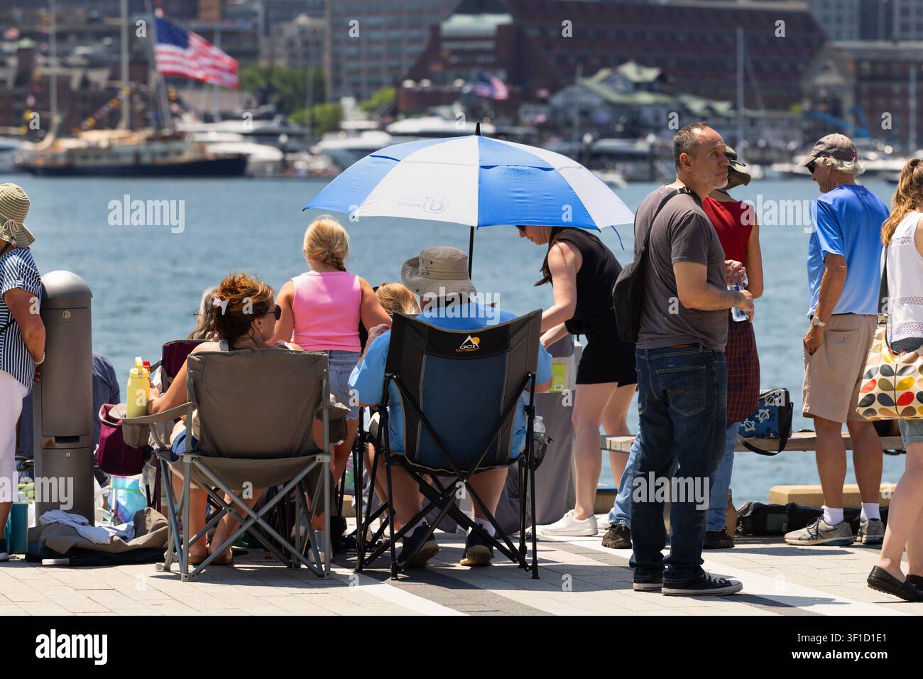 Gli spettatori osservano la Parata delle Vele dal lungomare di East Boston, con barche e il centro di Boston dall'altra parte del porto. Foto Stock