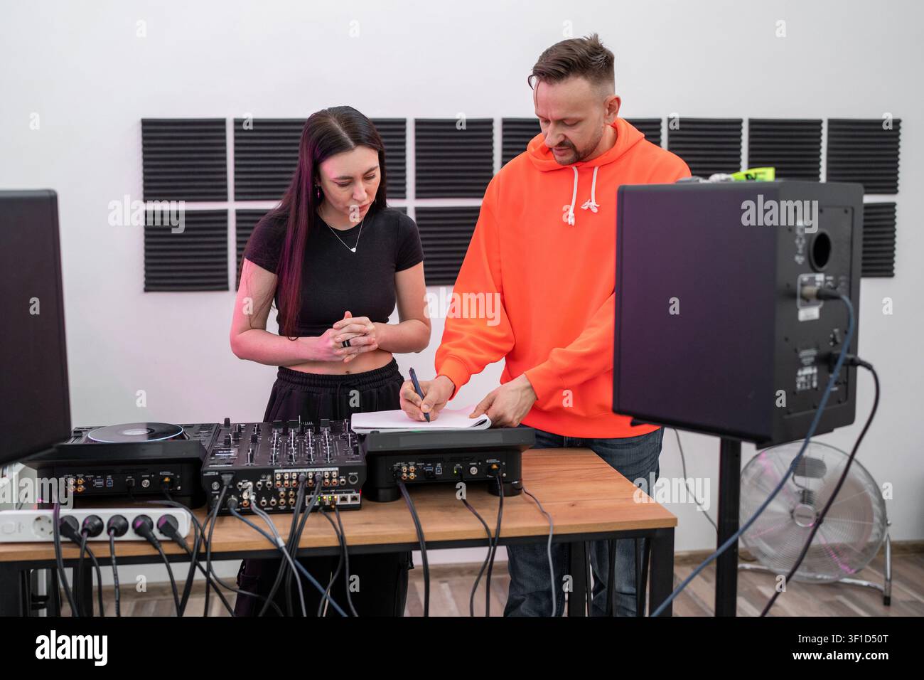 Donna che impara le abilità da DJ con console di mixaggio, lavora in modo indipendente alla scrivania dello studio di registrazione. DJ, donna, console di mixaggio, apprendimento, studio Foto Stock