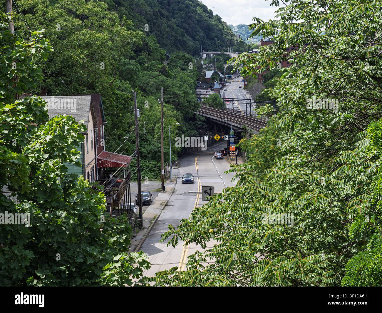 Pittsburgh PA Stati Uniti-06 21 2026: Una strada asfaltata curva bruscamente oltre proprietà residenziali su una collina ripida e alberata Foto Stock