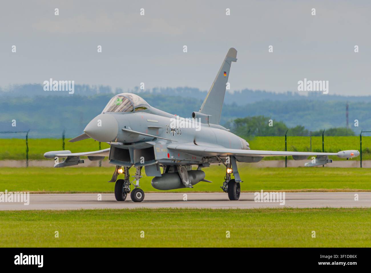 Aereo da combattimento multiruolo Eurofighter Typhoon in taxi sulla pista, vista laterale con equipaggio di terra, sfondo di paesaggio verde Foto Stock