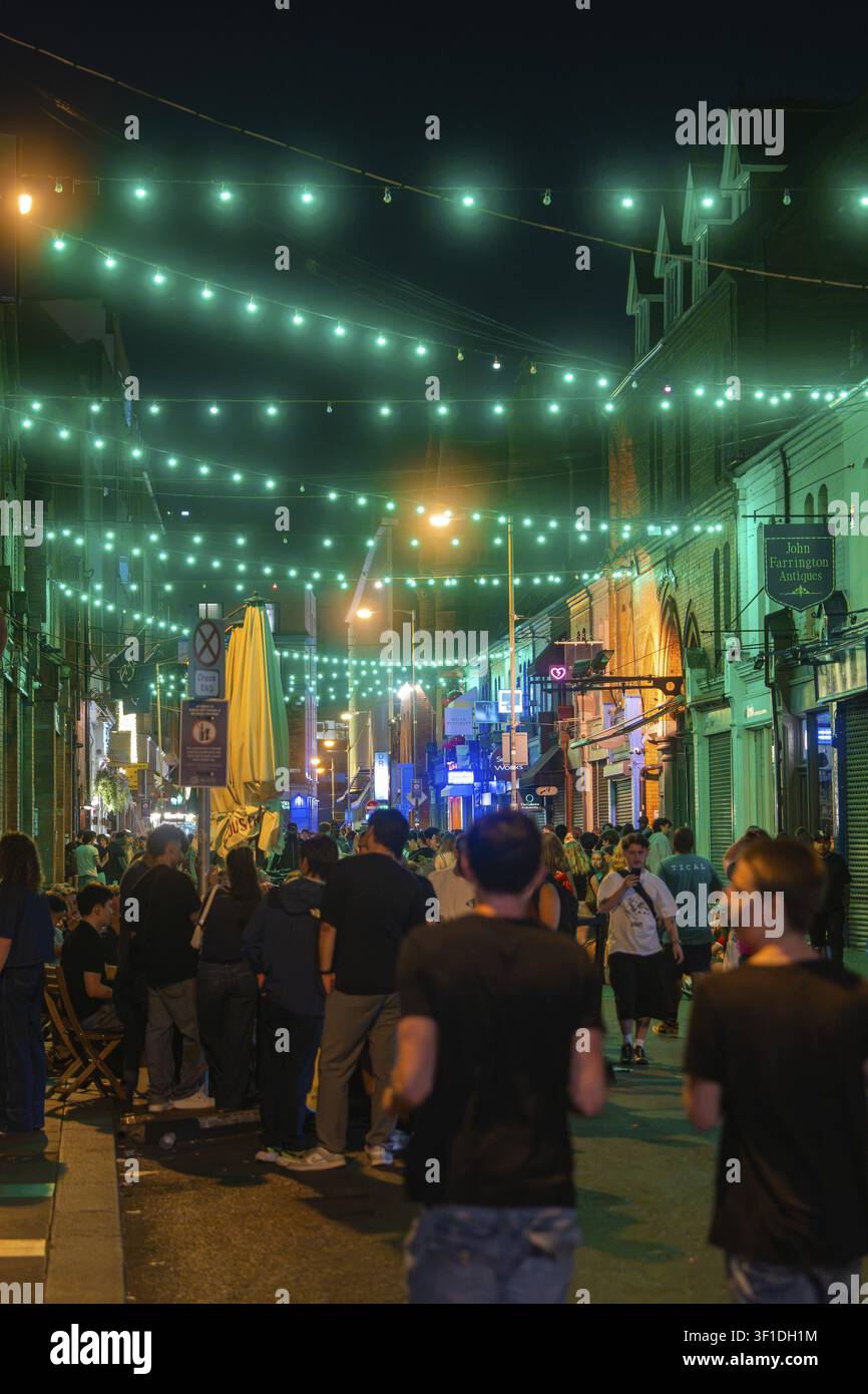 Strada di notte, coperta di luci verdi, piena di gente che festeggia, vita notturna, Dublino, Irlanda Foto Stock