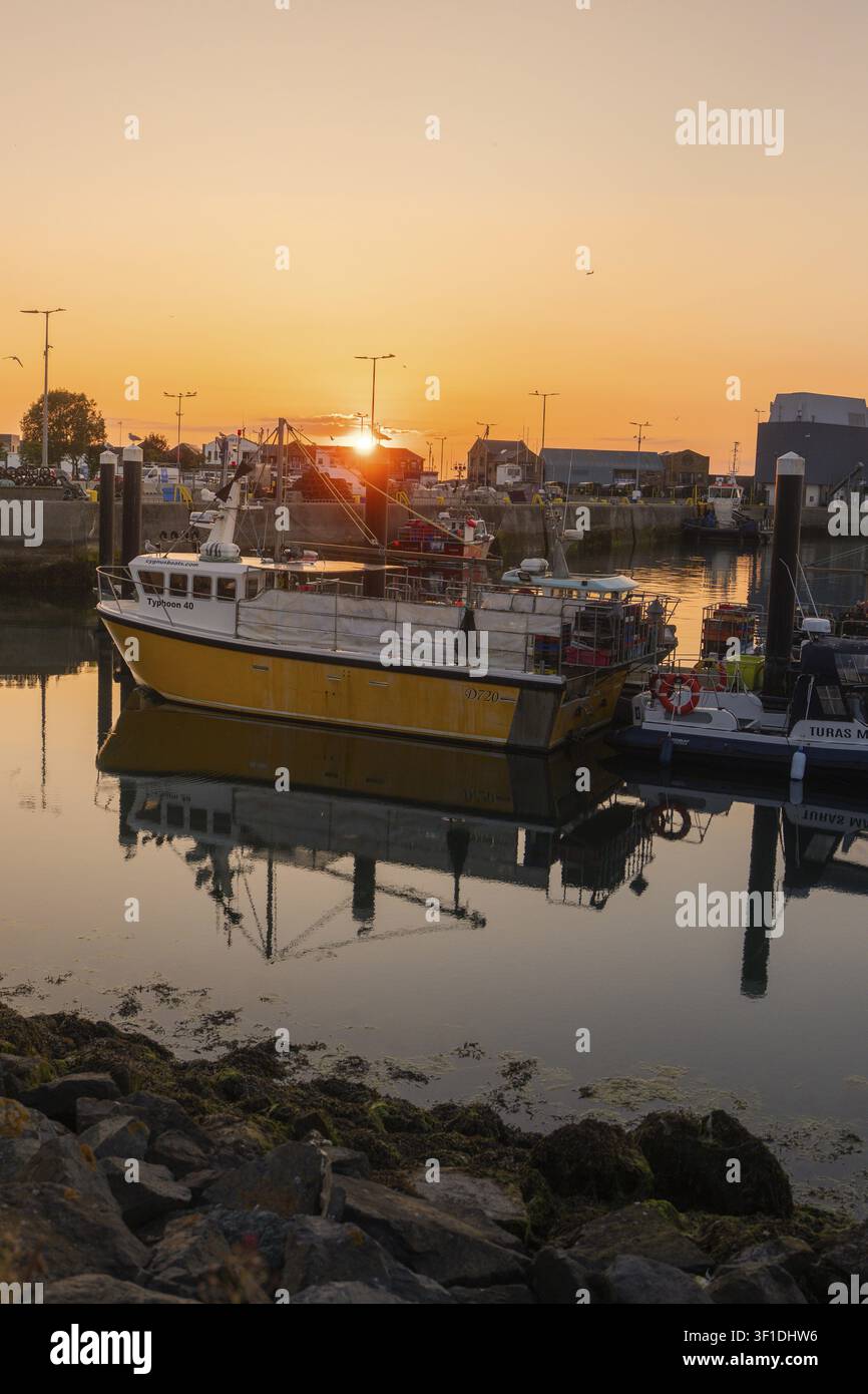 Barca da pesca nel porto al tramonto, acqua calma con riflessi e atmosfera tranquilla, Howth, Irlanda Foto Stock