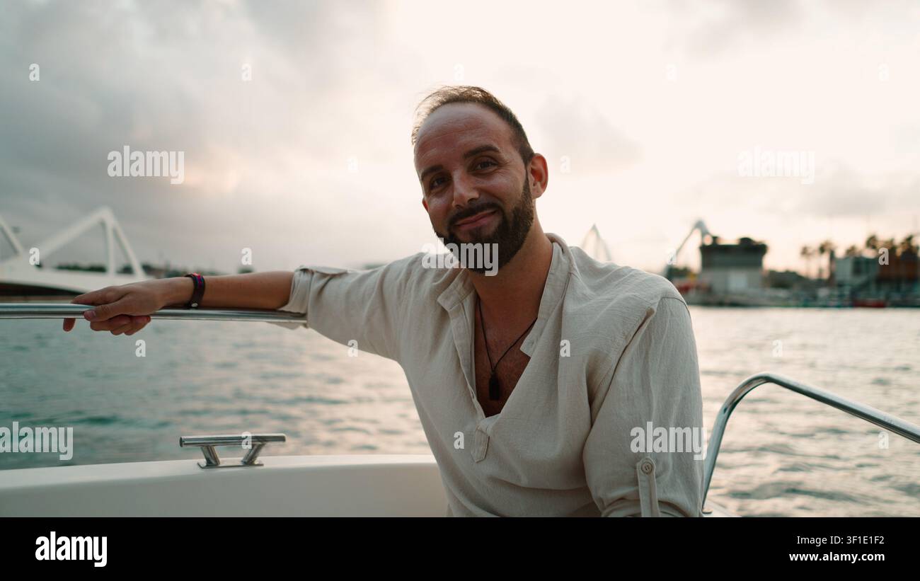 Uomo durante un'escursione in barca che sorride, porto e ponte dietro di lui Foto Stock
