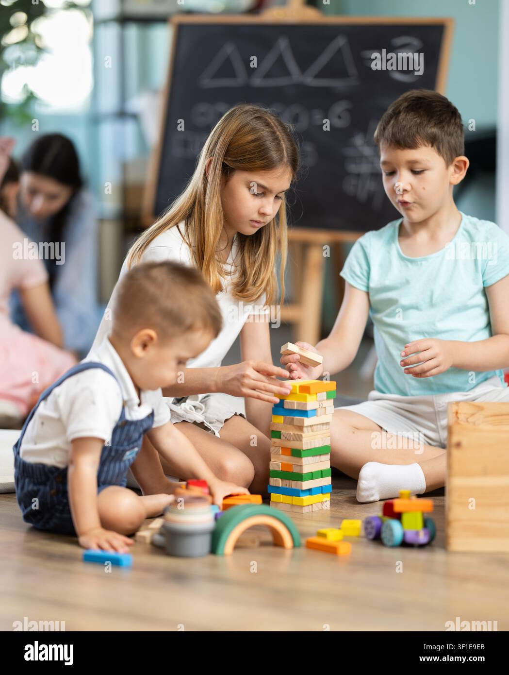 Bambini che giocano con giocattoli seduti sul pavimento nell'asilo Foto Stock