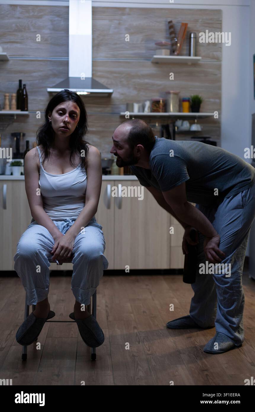 Uomo violento che minaccia una partner abusata e in difficoltà con lividi, minacce e stress emotivo, mostrando l'impatto della violenza tra partner in una relazione problematica. Foto Stock