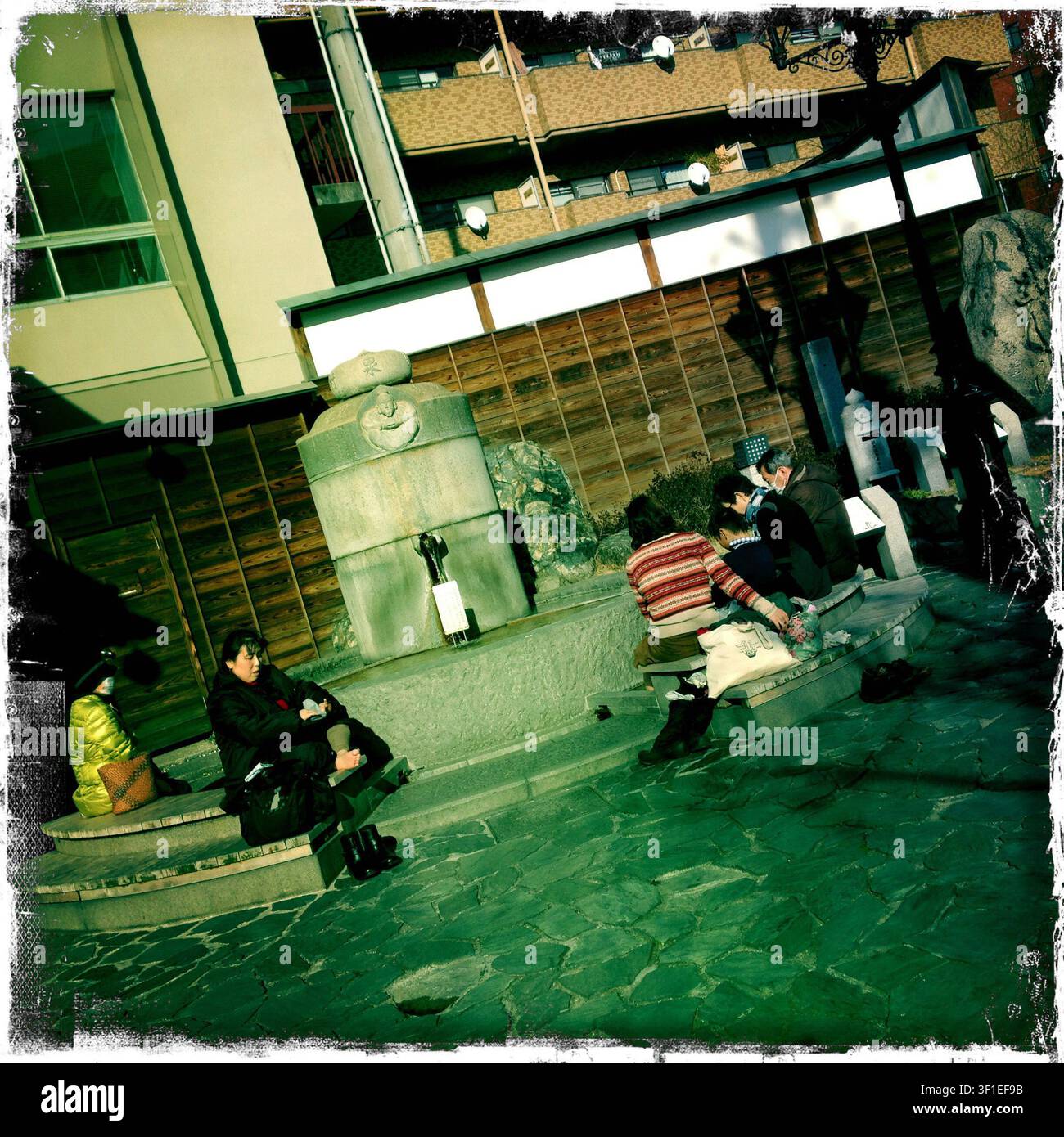 I visitatori immergono i loro piedi in un centro benessere per i piedi fuori dalla stazione di Dogo Onsen vicino a Dogo Onsen, considerata la più antica spa del Giappone nella città di Matsuyama, prefettura di Ehime, Giappone. Fotografo: Robert Gilhooly Foto Stock