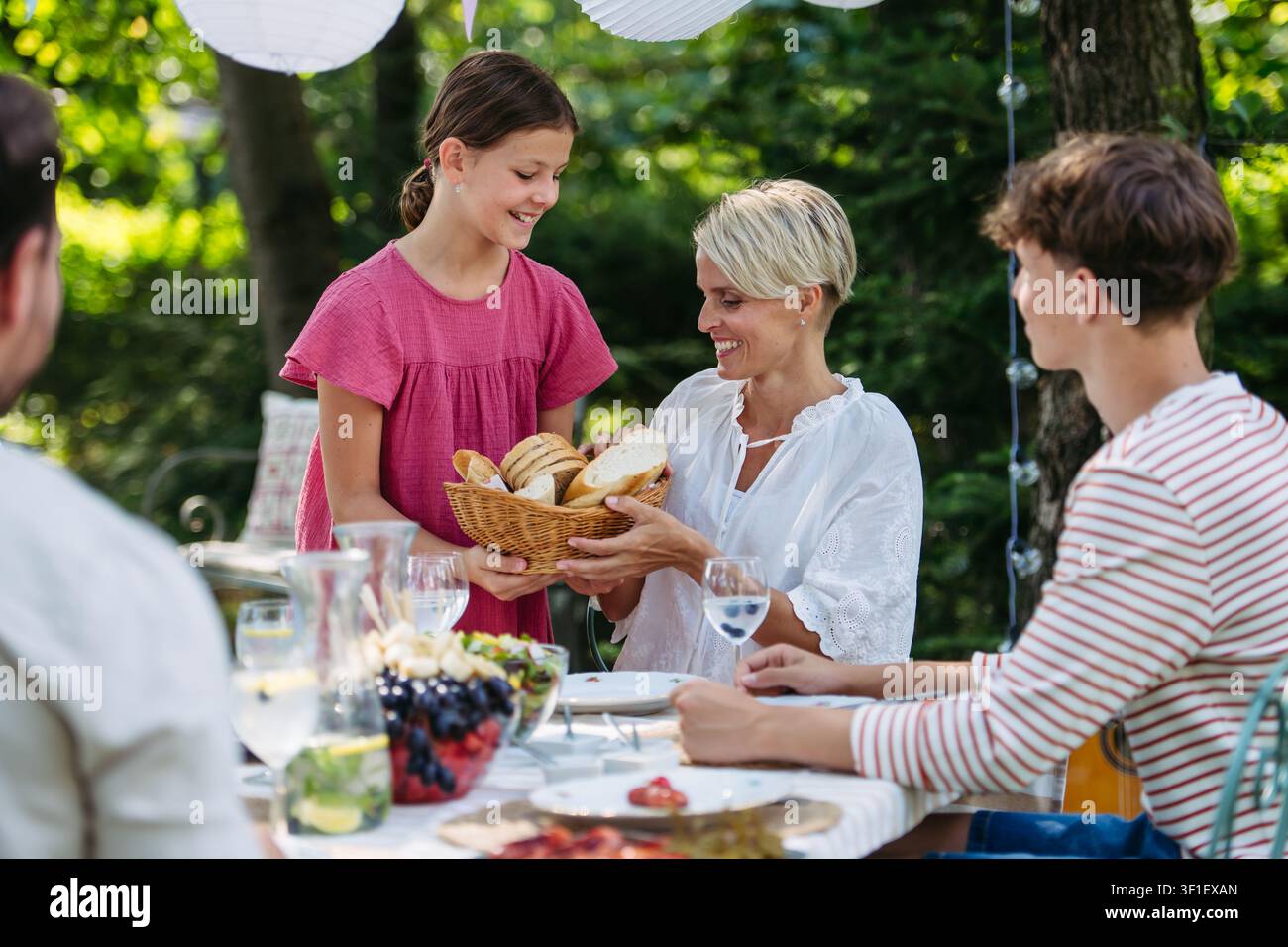 La famiglia condivide il cibo durante la festa al grill in giardino. Foto Stock
