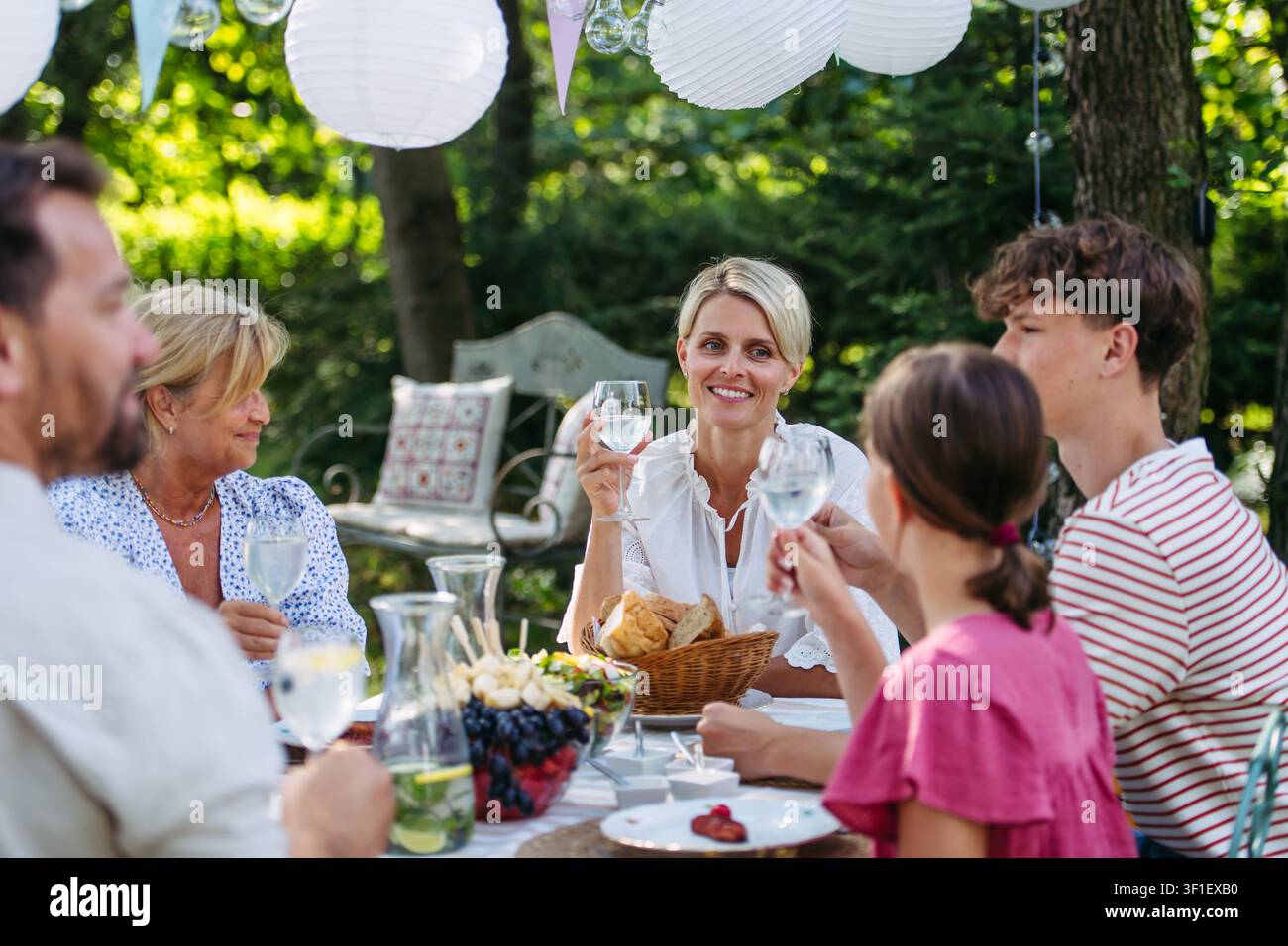 La famiglia condivide il cibo durante la festa al grill in giardino. Foto Stock