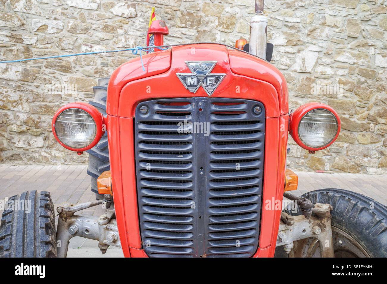 Castellgali - Spagna - 5 maggio 2026: Primo piano anteriore di un trattore vintage rosso con logo metallico classico, griglia di veicolo agricolo antico, fari rotondi Foto Stock